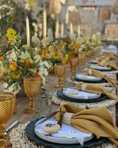 a long table set with place settings and flowers