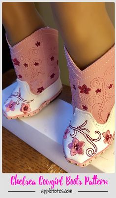 a pair of pink boots sitting on top of a white platform with flowers painted on them