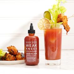 a drink and some food are sitting on a table next to each other, with the bottle in front of it