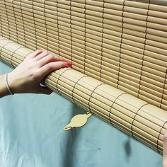 a woman is placing bamboo blinds on the wall