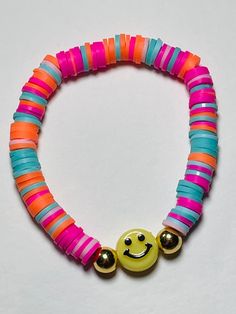 a smiley face beaded bracelet on a white surface with two beads attached to it