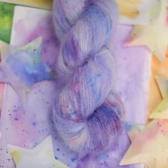 a skein of purple yarn sitting on top of colorful paper with stars in the background