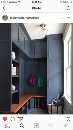 a room that has some blue cabinets and wooden shelves on the wall, with green towels hanging from them