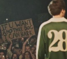 a man standing in front of a crowd holding a sign with the number 28 on it