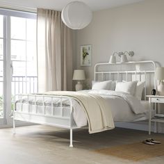 a white bed sitting in a bedroom next to a window