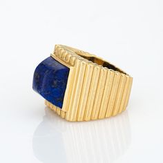 This is part of Chairish’s Fine Jewelry assortment.  Vintage Tiffany & Co lapis lazuli ring crafted in 18 karat yellow gold (circa 1970s).    Lapis lazuli measures 11mm diameter. The lapis is in good condition with some minor abrasions visible under a 10x loupe.  Dating to the 1970s the 18k gold ring is styled in a ridged square design. The sugarloaf cut cobalt blue lapis lazuli makes a great statement. The ring is a great example of 70s era design with a bold, distinct look that makes an impact Yellow Gold Lapis Lazuli Gemstone Rings, Yellow Gold Rings With Lapis Lazuli Gemstone, Yellow Gold Lapis Lazuli Ring With Polished Finish, Luxury Lapis Lazuli Gemstone Rings, Luxury Yellow Gold Cabochon Signet Ring, Luxury Yellow Gold Signet Ring With Cabochon, Luxury Lapis Lazuli Jewelry, Anniversary Yellow Gold Lapis Lazuli Rings, Luxury Oval Lapis Lazuli Rings