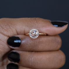 a close up of a person's hand holding a ring with a diamond on it