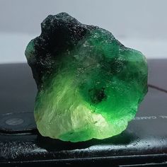 a green rock sitting on top of a cell phone