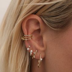 a woman wearing three different types of ear piercings on her left ear and the other one is gold