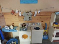 a toy kitchen with washing machine and dryer in the corner next to other toys