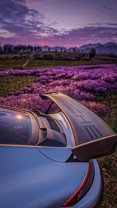 a silver sports car parked in front of purple flowers