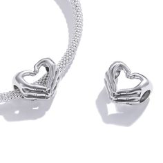 Celebrate your love with this brightly polished sterling silver heart charm! This sterling silver heart charm features two hands making a heart gesture. Keep this little heart as a reminder of affection and commitment between two people. Or give this meaningful heart charm as a gift to your special someone. Features: Compatible with All Major Brand Charm Bracelets Material: Sterling Silver Nickel-Free Hyperallergic High-Polish Finish Charm hole diameter: 0.18" | 4.5 mm Charm Height: 0.43" | 10.9 Nickel Free Silver Heart Charms, Sterling Silver Heart Jewelry For Friendship, Silver Sterling Silver Heart Charms, White Gold Heart Charms In Sterling Silver, Double Heart Charm For Gifts, Silver Heart Charm As A Gift, White Gold Heart Pendant Charm In Sterling Silver, White Gold Sterling Silver Heart Charms, Silver Heart Pendant Charm In Sterling Silver