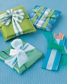 four folded gift boxes with bows and ribbons on them, all wrapped in blue and green paper