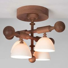 three light wooden fixture with white glass shades on the bottom and two lights above them