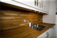 a kitchen with wooden counter tops and white cupboards on either side of the sink