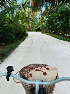 a bicycle is parked on the side of a dirt road with palm trees in the background