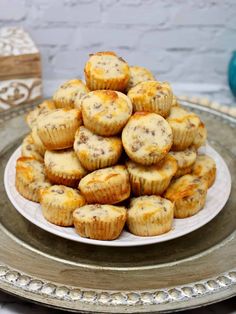 a white plate topped with muffins on top of a silver tray next to a box of cookies