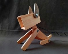 a wooden toy dog sitting on top of a black table next to a light bulb