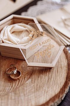 two wedding rings in a wooden box on top of a piece of wood that has been carved into it