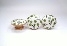 three ceramic knobs with green and white flowers on them, sitting next to each other