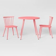 two pink chairs and a table on a white background, with one chair in the middle