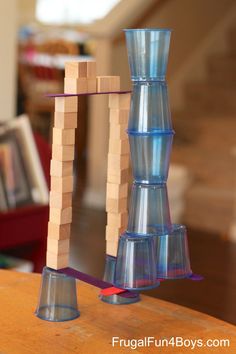 a stack of blocks sitting on top of a wooden table next to a glass vase