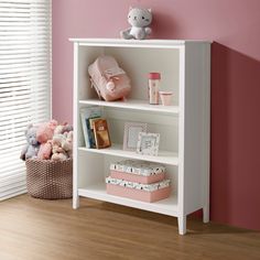 a white book shelf sitting next to a pink wall