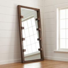 a large mirror sitting on top of a wooden floor next to a window in a room