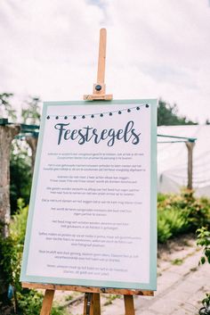 a sign that is sitting on a easel in front of some plants and flowers