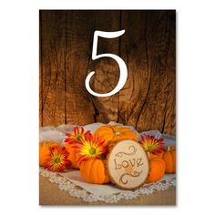 a table number with pumpkins and flowers on it