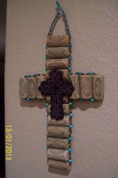 a cross made out of wine corks hanging from the wall with beads on it