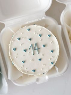 a white cake with blue hearts and the number four on it in a plastic container