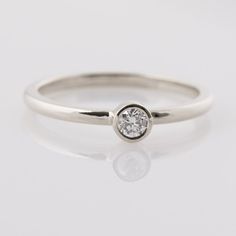 a white gold ring with a single diamond in the center, on a plain surface