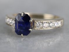 "We love the elegant style of this timeless engagement ring. The tapered, milgrain sides are interesting, and the top of the shoulders have a beautiful curve, set with bright diamonds. The center stone is a deep, excellent shade of navy blue. This color is the benchmark for fine Sapphire, and indicative of Sri Lanka, where we purchased the stone! A perfectly balanced one carat in weight and of the highest possible quality, this engagement ring will be treasured for decades to come. Metal: 14K Wh Yellow Gold Sapphire Ring, Sapphire And Diamond Engagement Ring, White Gold Sapphire Ring, Sapphire Anniversary, Timeless Engagement Ring, Right Hand Ring, Gold Sapphire Ring, Ring Sapphire, White Gold Sapphire