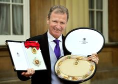 a man in a suit and tie holding up two different types of jewelry boxes with medals on them