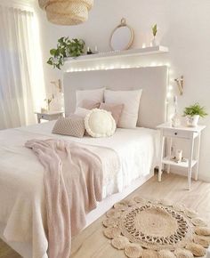 a bedroom with white walls and wooden flooring is lit up by lights above the bed