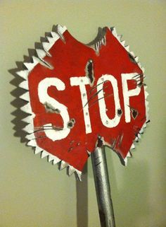 a red stop sign sitting on top of a metal pole next to a white wall