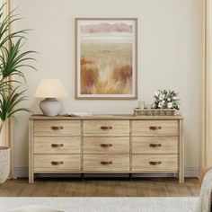 a living room scene with focus on the chest of drawers and a painting hanging above it