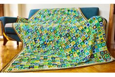 a green and blue blanket sitting on top of a wooden floor next to a chair