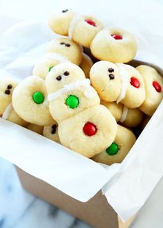 a box full of cookies with white frosting and green candies on top, sitting on a table