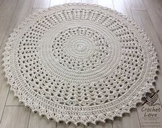 a white crocheted doily is laying on the floor next to a wooden floor