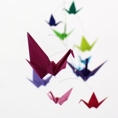 several origami birds are flying in the sky