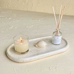 a candle and some sea shells on a tray