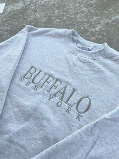 Introducing the Buffalo Beige Embroidered Crewneck, a comfortable and stylish  sweatshirt with a unique minimalist design that adds a touch of color to your wardrobe. Made with a blend of 50% cotton and 50% polyester, this sweatshirt is soft, cozy, and durable.  Product details: 50% cotton, 50% polyester blend Available in multiple sizes S-5X Care: Machine wash gentle cold inside out with like colors. Hang Dry Gray Relaxed Fit Tops With Embroidered Logo, Gray Tops With Embroidered Logo, Relaxed Fit, Basic Sweatshirt With Embroidered Text And Relaxed Fit, Basic Relaxed Fit Sweatshirt With Embroidered Text, Basic Sweatshirt With Relaxed Fit And Embroidered Text, Trendy Embroidered Logo Tops For Loungewear, Long Sleeve Tops With Embroidered Logo For Loungewear, Relaxed Fit Embroidered Sweatshirt For Everyday, Everyday Relaxed Fit Sweatshirt With Embroidered Text