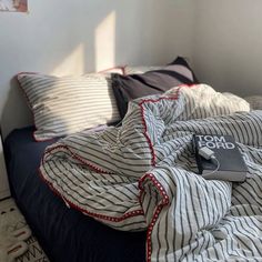 an unmade bed with striped sheets and pillows