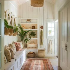 a hallway with white walls and lots of plants on the shelves, along with a large rug