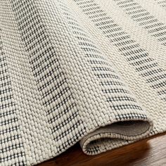 a close up view of a rug on a wooden floor with a white and black checkered pattern