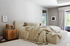 a bedroom with a large bed covered in a beige blanket and blankets on top of it