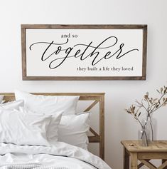 a bed with white sheets and pillows next to a wooden sign that says, and so together they build a life they loved