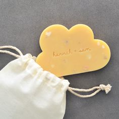 a yellow cloud shaped soap sitting on top of a white drawstring bag next to it